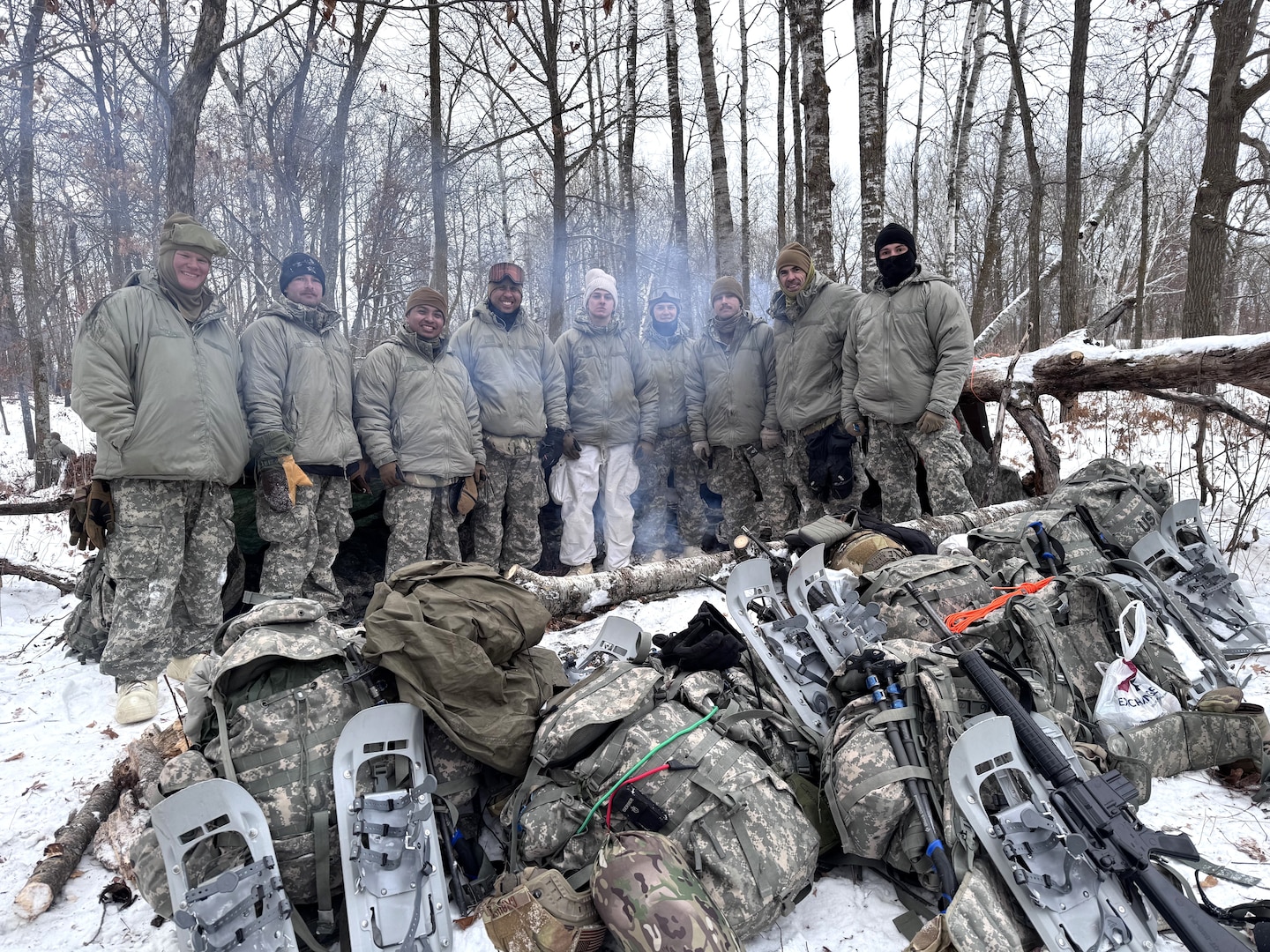 A team of Air National Guard Airmen stand in front of a thermal shelter built using limited supplies and materials found in nature during the Air National Guard's Cold Weather Operations Course at Camp Ripley Training Center, Minn., Feb. 4, 2025.