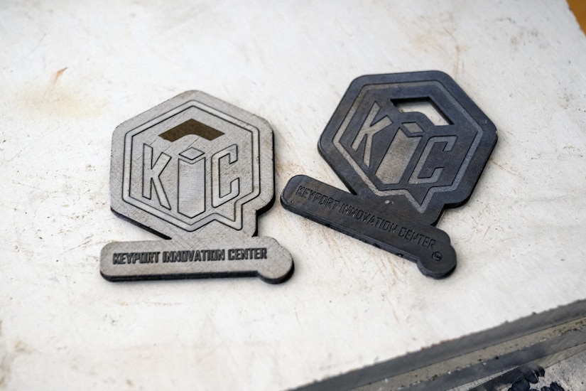 Two thin pieces of printed metal show an engraved emblem for the Keyport Innovation Center.