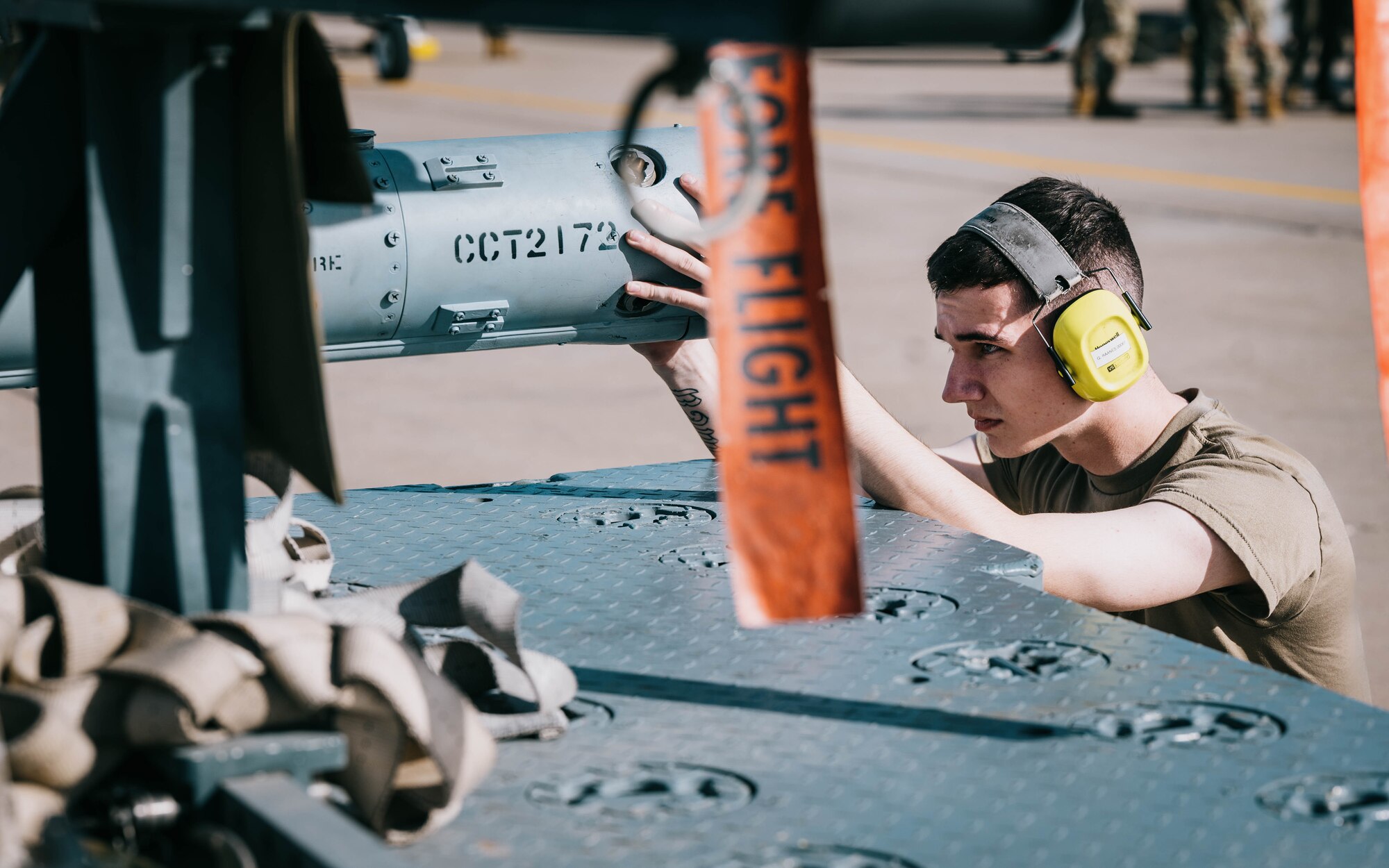 U.S. Air Force Airman 1st Class Gabriel Raanes, 310th Aircraft Maintenance Unit weapons load crew member, fastens an AIM-120 Advanced Medium-Range Air-to-Air Missile to a trailer.