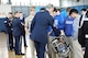 An Air Force Airman is leaning over to show high school students a drum. They are in a gymnasium.