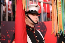 A Marine is standing on the sidelines at Super Bowl LIX holding a flag, waiting to present the colors on the field.