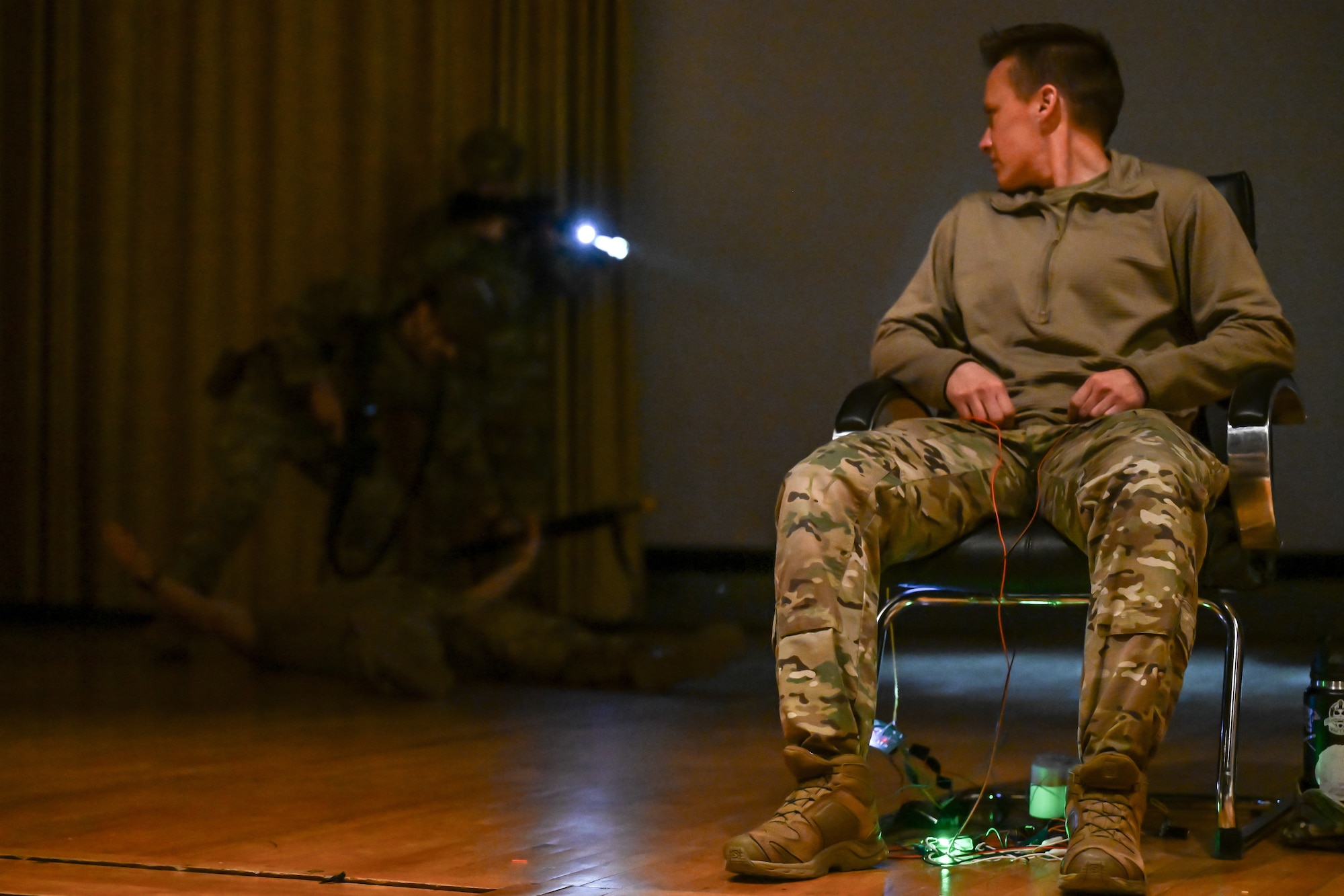 An airman sits in a chair acting as a hostage