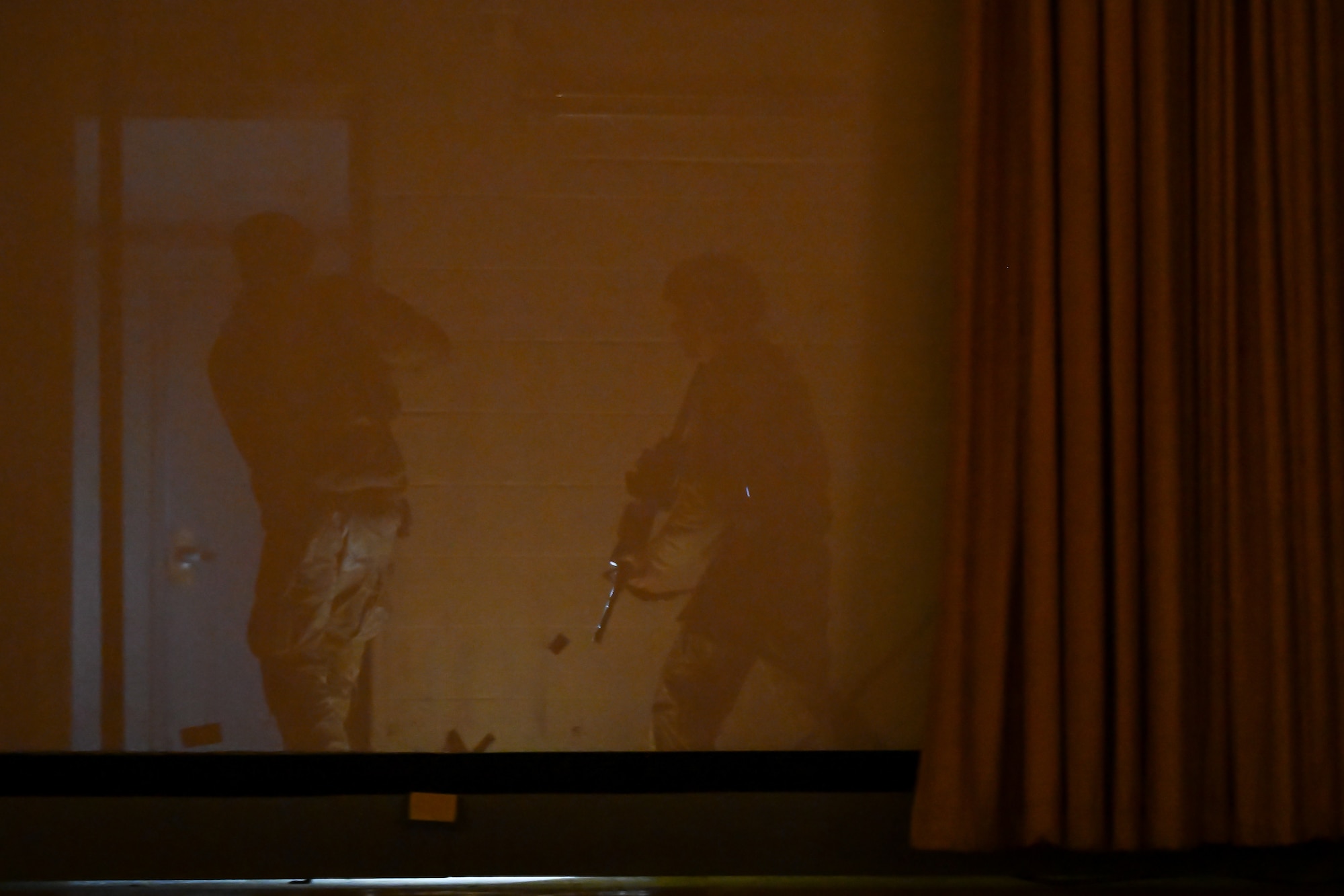Airman search behind the theater screen during a hostage rescue training exercise