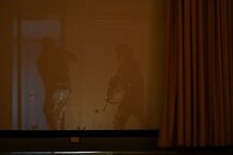 Airman search behind the theater screen during a hostage rescue training exercise