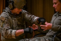 An airman tapes explosive wires to another airman acting as an hostage