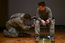 An Airman examines under the chair of a hostage actor