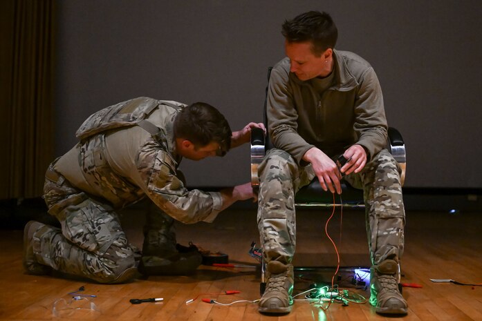 An Airman examines under the chair of a hostage actor