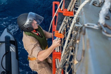 SOUTH CHINA SEA (Feb. 6, 2025) Lt. j. g. Peter Greenbaum, a junior officer stationed aboard the Arleigh Burke-class guided-missile destroyer USS Benfold (DDG 65), climbs a ladder up the starboard side of USS Benfold during multilateral operations with Australia and the United Kingdom in the South China Sea, Feb. 6. Benfold is forward deployed and assigned to Destroyer Squadron (DESRON) 15, the Navy’s Largest DESRON and U.S. 7th Fleet’s principal surface force. (U.S. Navy Photo by Mass Communication Specialist 2nd Class Monica Walker.)