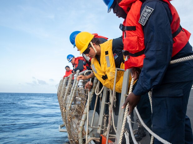 SOUTH CHINA SEA (Feb. 6, 2025) Sailors assigned to the Arleigh Burke-class guided missile destroyer USS Benfold (DDG 65) lower a ladder from the flight deck during multilateral operations with Australia and the United Kingdom in the South China Sea, Feb. 6. Benfold is forward deployed and assigned to Destroyer Squadron (DESRON) 15, the Navy’s Largest DESRON and U.S. 7th Fleet’s principal surface force. (U.S. Navy Photo by Mass Communication Specialist 2nd Class Monica Walker.)