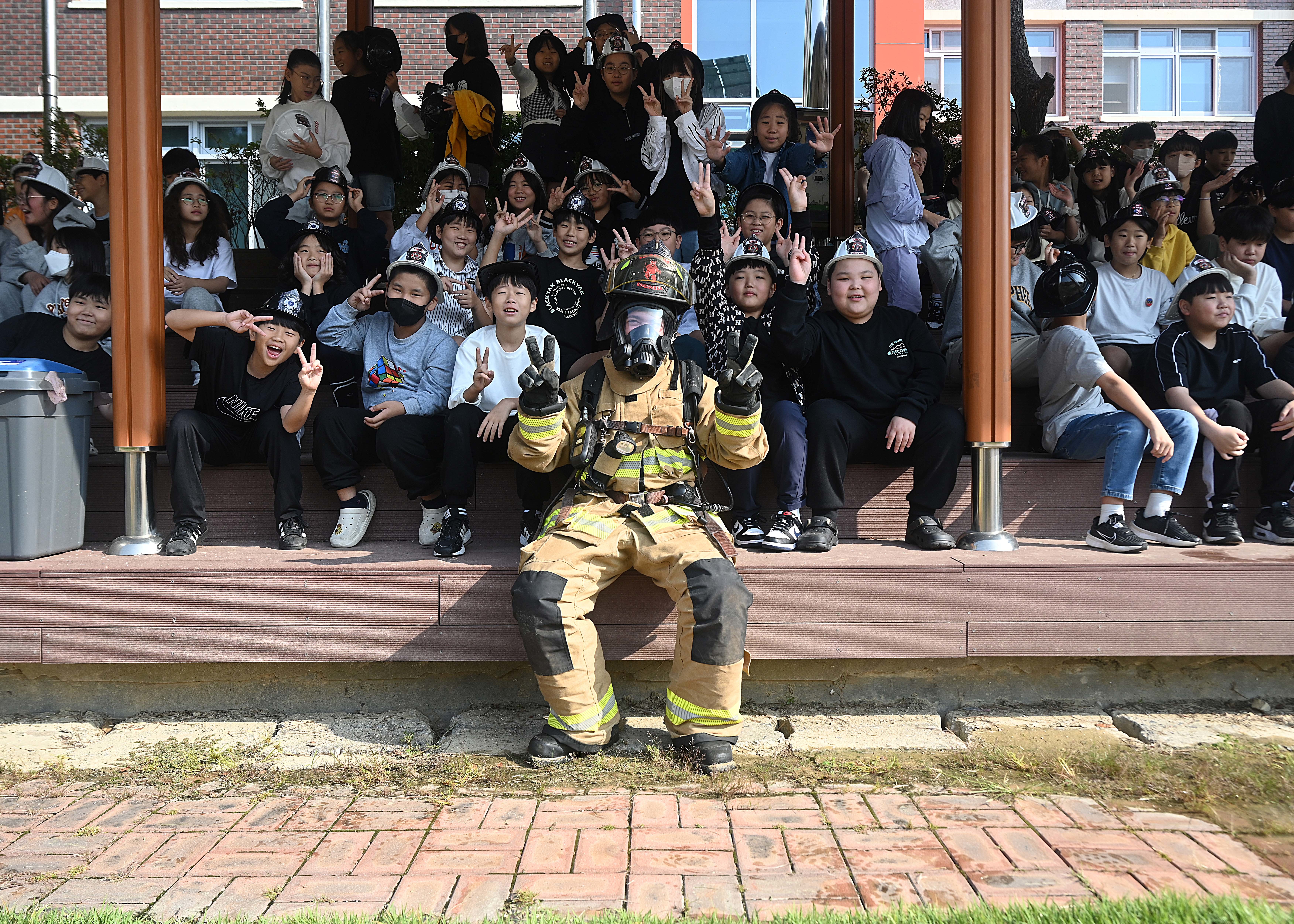 U.S. Air Force Senior Airman Adam Olea, 8th Civil Engineer Squadron Fire Department driver operator, sits with students from Jigok Elementary School during a visit for Fire Prevention Week Oct. 8, 2024, at Gunsan, Republic of Korea.