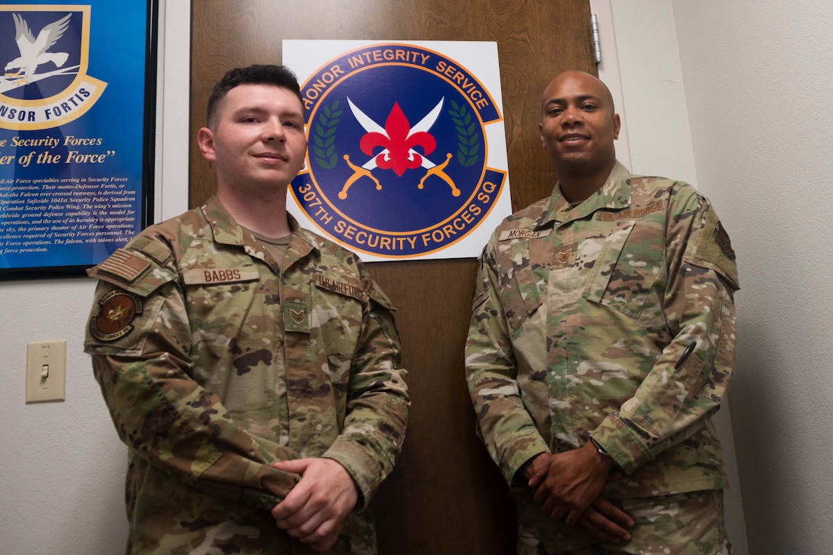 Two Airmen pose by their unit patch.