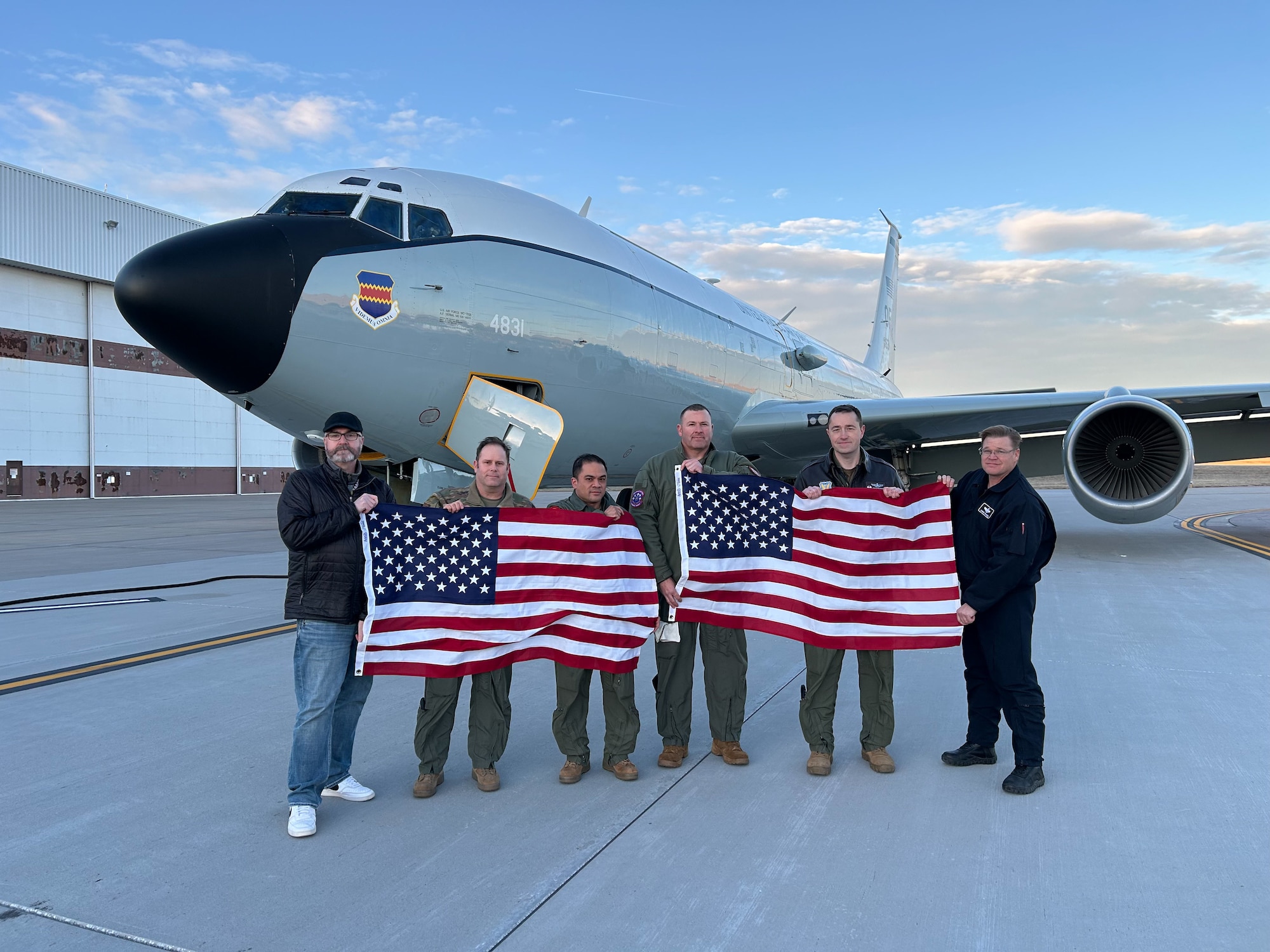 People pose in front of an aircraft holding American flags