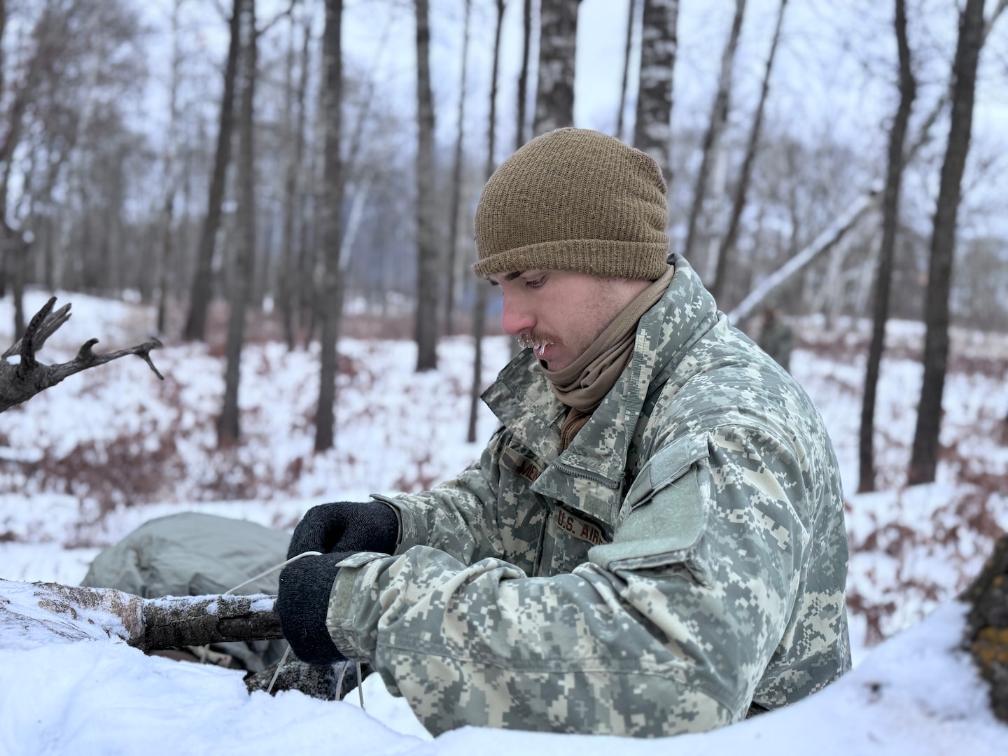 An Air National Guard Airmen helps build a thermal shelter using limited supplies and materials found in nature during the Air National Guard's Cold Weather Operations Course at Camp Ripley Training Center, Minn., Feb. 4, 2025. 70 class participants representing 37 wings from 27 states traveled on foot in subzero temperatures, to build camps featuring either a 10-man Arctic tent or thermal shelters made from materials found in nature. Students were mostly Security Forces specialists, but also included a Maintenance Group Commander, Physician Assistant, Cyber Communications Specialist, and a Public Affairs Specialist. The 2-week course featured a six-day, five-night field training exercise, taught service members to conduct mission-essential tasking in extreme cold environments.