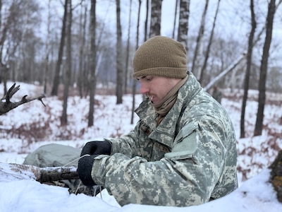 An Air National Guard Airmen helps build a thermal shelter using limited supplies and materials found in nature during the Air National Guard's Cold Weather Operations Course at Camp Ripley Training Center, Minn., Feb. 4, 2025. 70 class participants representing 37 wings from 27 states traveled on foot in subzero temperatures, to build camps featuring either a 10-man Arctic tent or thermal shelters made from materials found in nature. Students were mostly Security Forces specialists, but also included a Maintenance Group Commander, Physician Assistant, Cyber Communications Specialist, and a Public Affairs Specialist. The 2-week course featured a six-day, five-night field training exercise, taught service members to conduct mission-essential tasking in extreme cold environments.