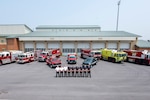 men stand in a line in front of fire tucks