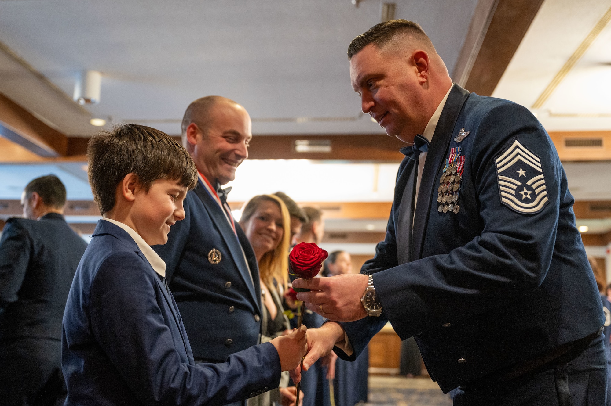 A Team Ramstein member receives a rose from U.S. Air Force Chief Master Sgt. Louis Ludwig, 86th AW command chief, at Ramstein Air Base, Germany, Feb. 7, 2025. The ceremony recognized nominees and award winners for their accomplishments and contributions in 2024.