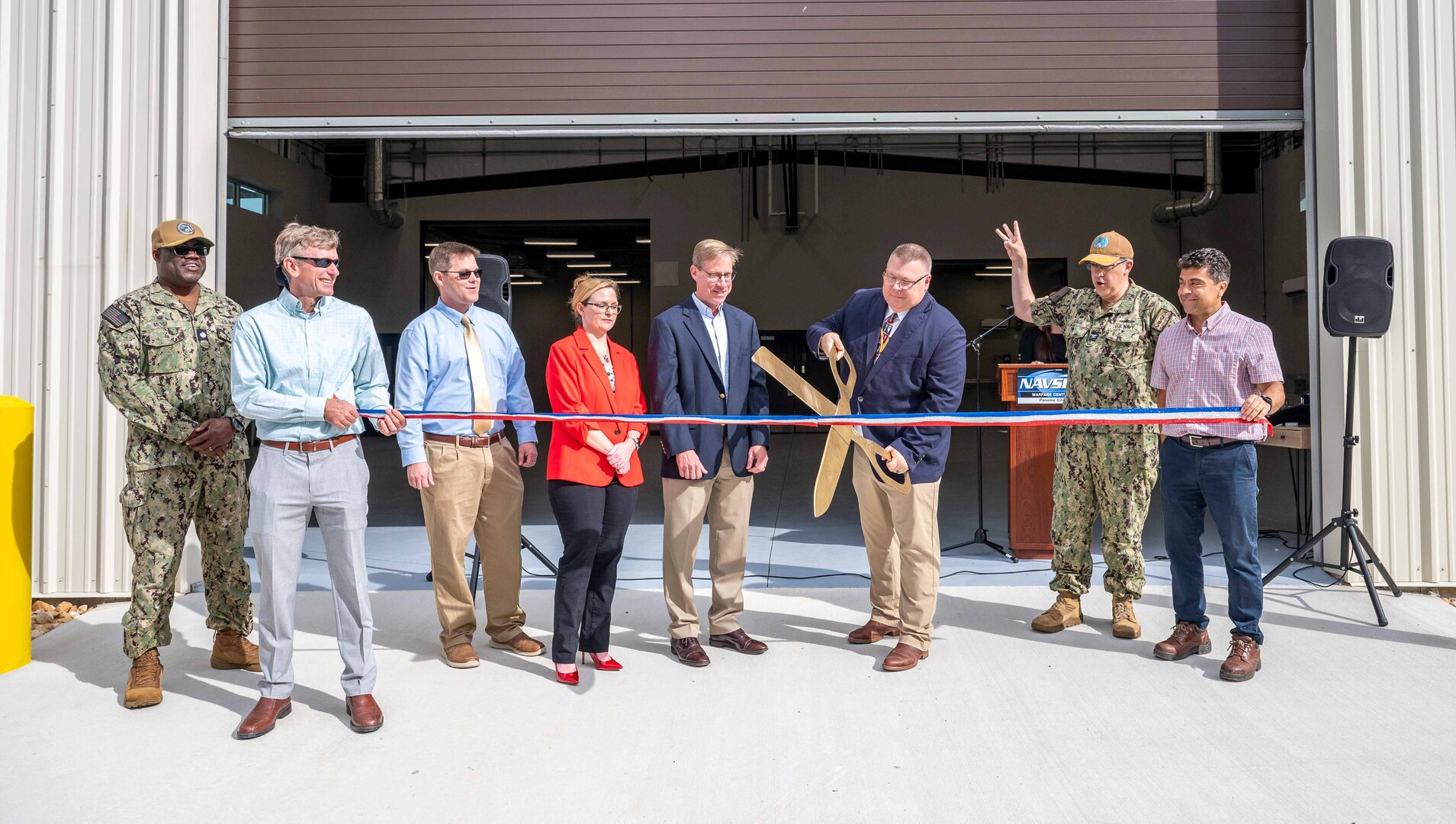 A ribbon-cutting ceremony for Naval Surface Warfare Center Panama City Division’s new Air Cushion Vehicle Depot Facility was held here as the official party did the honors, Dec. 5. (from left) Cmdr. Michael Mosi, Cyril Gazignaire, Robert Moore, Amanda Davis, Dr. Peter Adair, Jim Wolf, Capt. David Back, and Oscar Bernal. (U.S. Navy photo by MC1 Kyle Merritt)