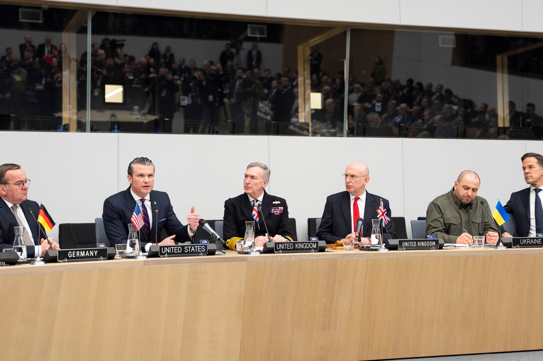Defense Secretary Pete Hegseth gestures while speaking at a table, as leaders seated near him look on.