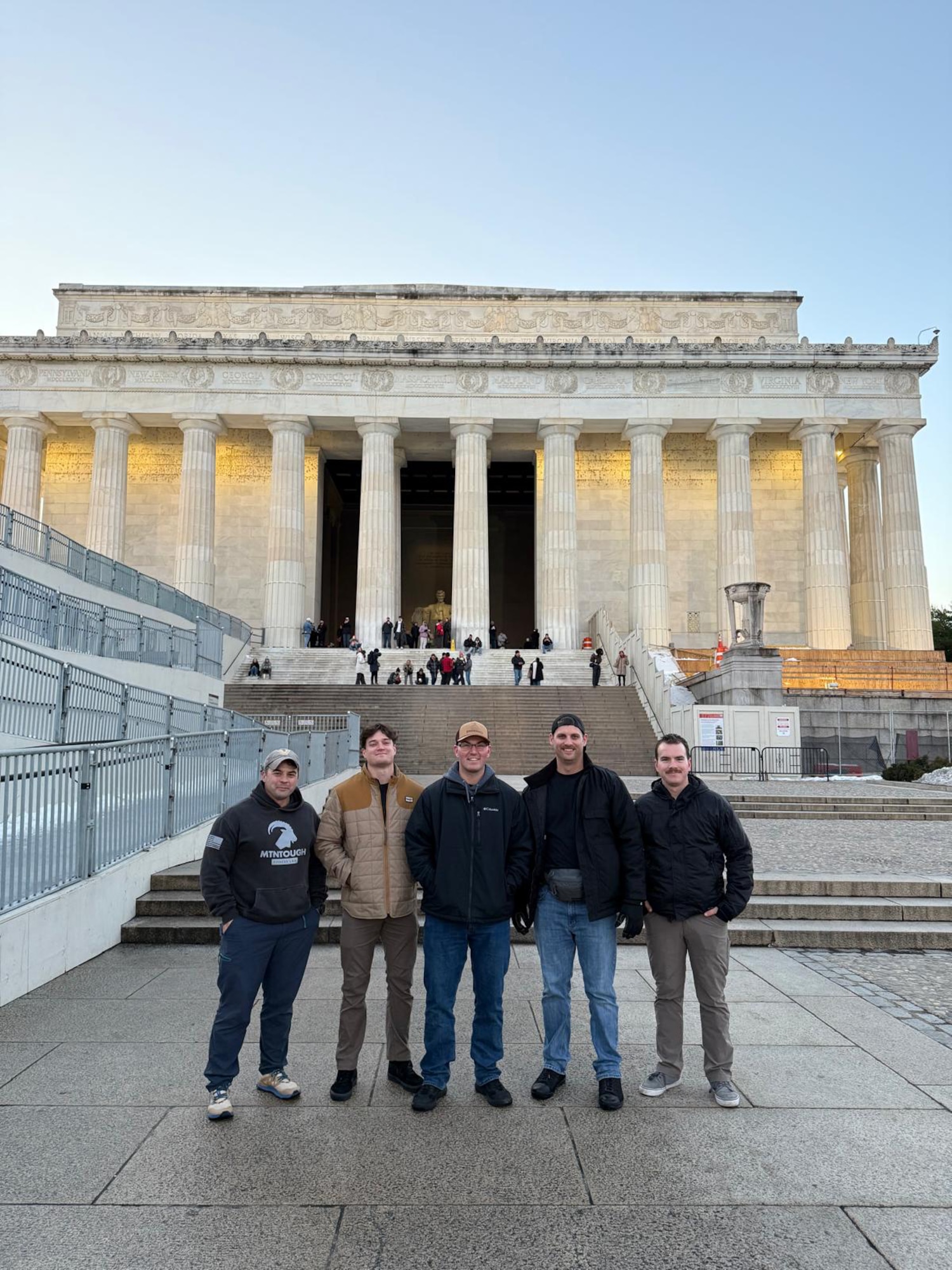 A group of people stand in front of the Lincoln Memorial