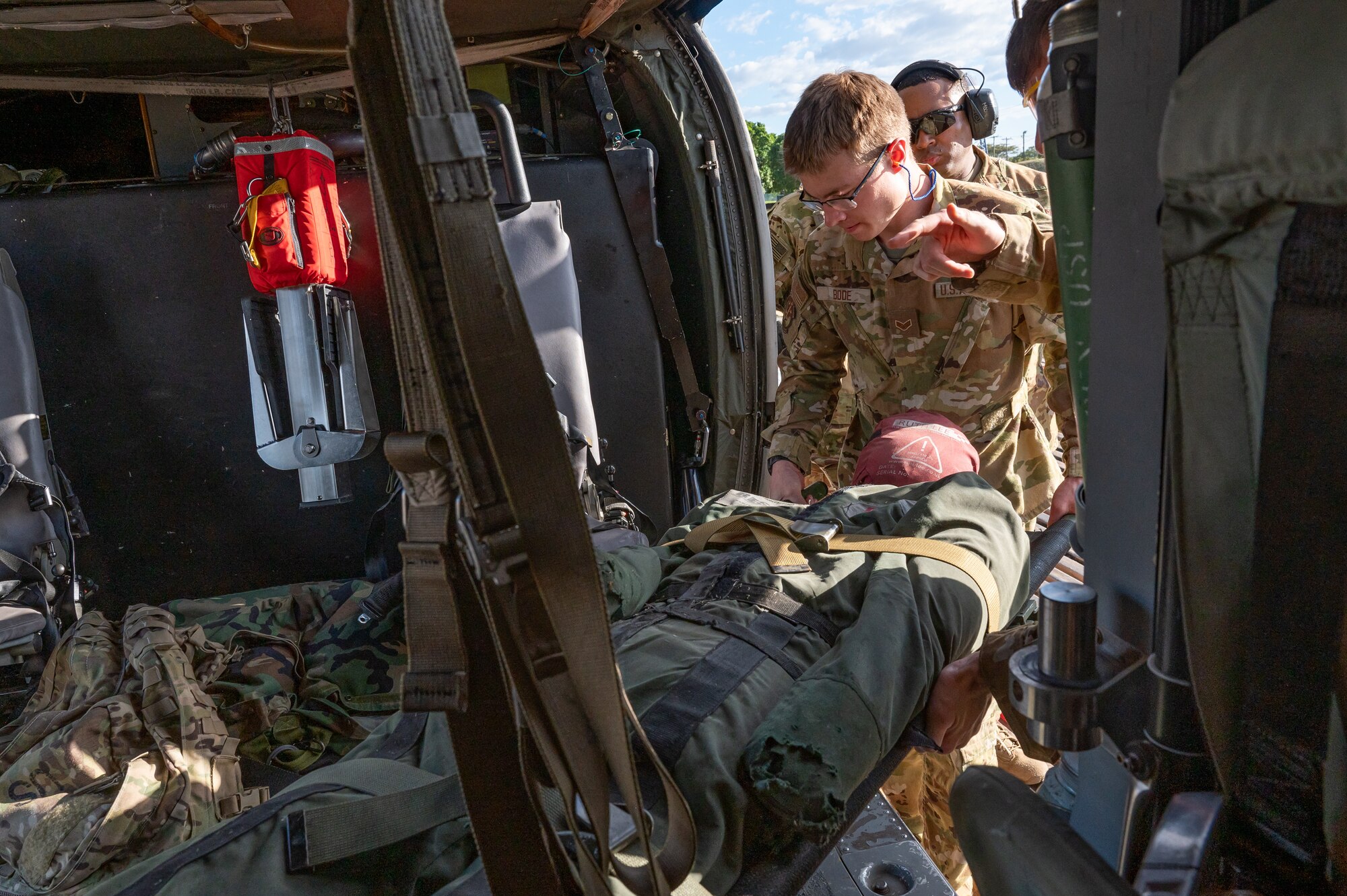 Joint Task Force-Bravo load a dummy patient into a helicopter during an air enroute care training at Soto Cano Air Base, Honduras, February 5, 2025. During the three day training members learned how to assess, care for and safely load a patient into a helicopter in case of a medical evacuation. (U.S. Air Force photo by Staff Sgt. Tristan Biese)