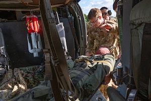 Joint Task Force-Bravo load a dummy patient into a helicopter during an air enroute care training at Soto Cano Air Base, Honduras, February 5, 2025. During the three day training members learned how to assess, care for and safely load a patient into a helicopter in case of a medical evacuation. (U.S. Air Force photo by Staff Sgt. Tristan Biese)