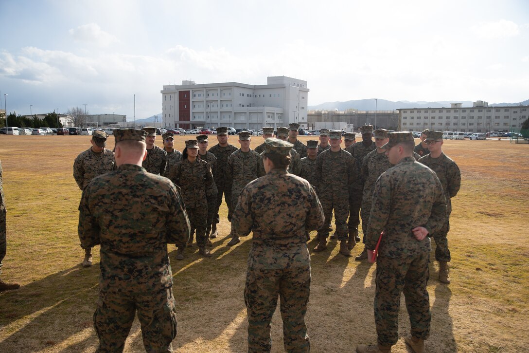 U.S. Marine Corps Maj. Kate Herren, center, the air traffic control facilities officer with Headquarters and Headquarters Squadron, Marine Corps Air Station Iwakuni, and a Washington native, speaks to Marines stationed at MCAS Iwakuni during a Navy and Marine Corps Achievement Medal award ceremony at MCAS Iwakuni, Japan, Jan. 29, 2025. Lance Cpl. Brandon Champagne received the Navy and Marine Corps Achievement Medal for rescuing two individuals trapped in wreckage after a vehicle accident while home on leave (U.S. Marine Corps photo by Cpl. Colin Thibault)