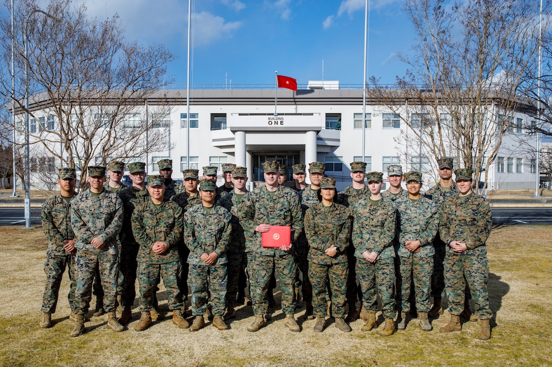 U.S. Marine Corps Lance Cpl. Brandon Champagne, center, an air traffic controller with Headquarters and Headquarters Squadron, Marine Corps Air Station Iwakuni, and a native of Florida, poses with Marines for a group photo after a Navy and Marine Corps Achievement Medal award ceremony at MCAS Iwakuni, Japan, Jan. 29, 2025. Lance Cpl. Champagne received the Navy and Marine Corps Achievement Medal for rescuing two individuals trapped in wreckage after a vehicle accident while home on leave. (U.S. Marine Corps photo by Lance Cpl. David Getz)