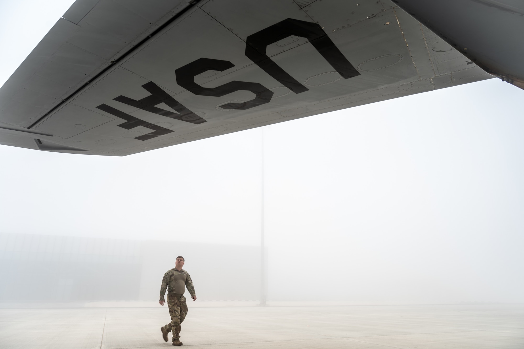 An Airman inspects the wing of an aircraft in the fog