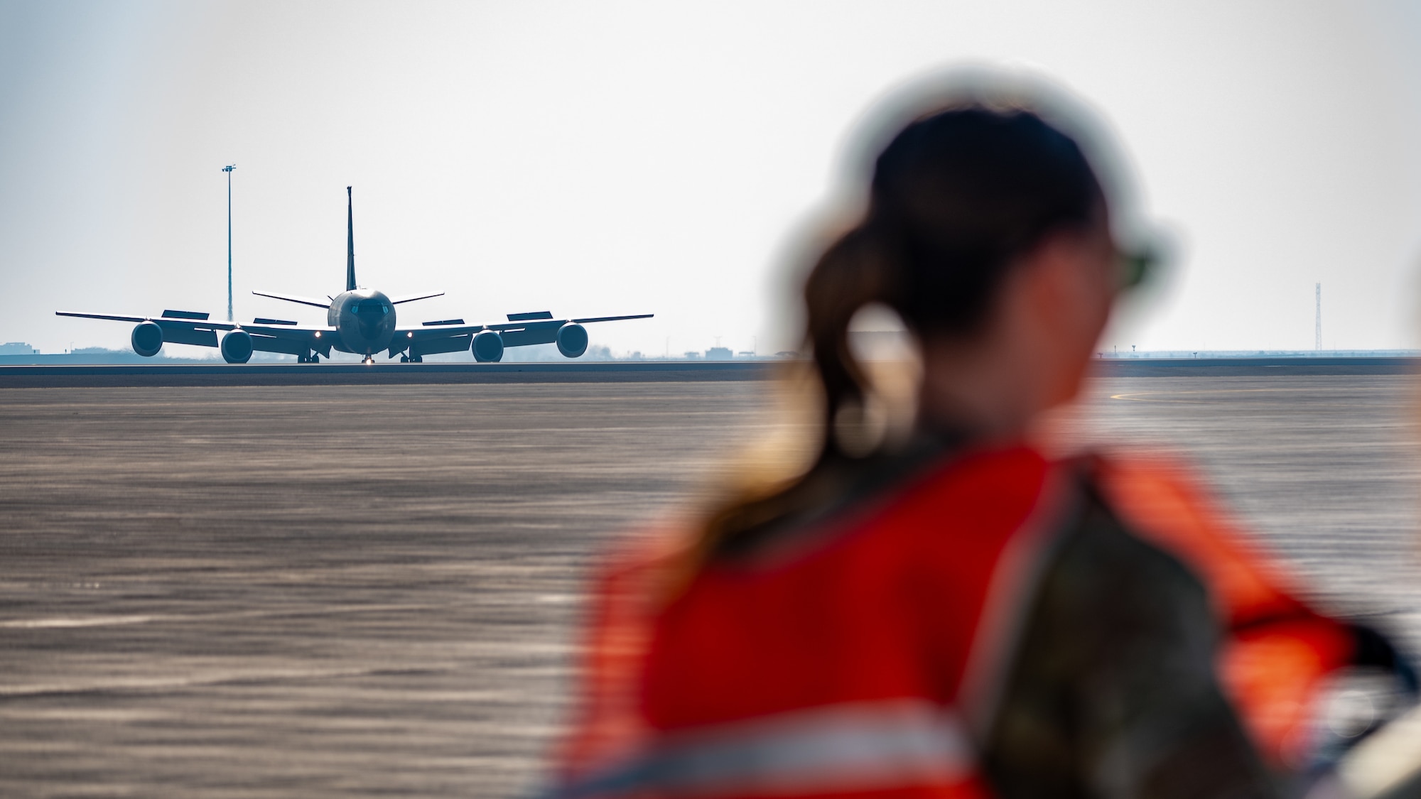 An Airman stands while a KC-135 taxis