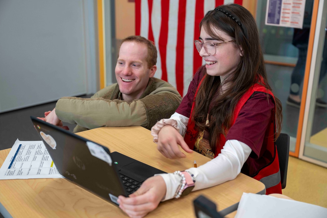 An Airmen and a student look at a laptop