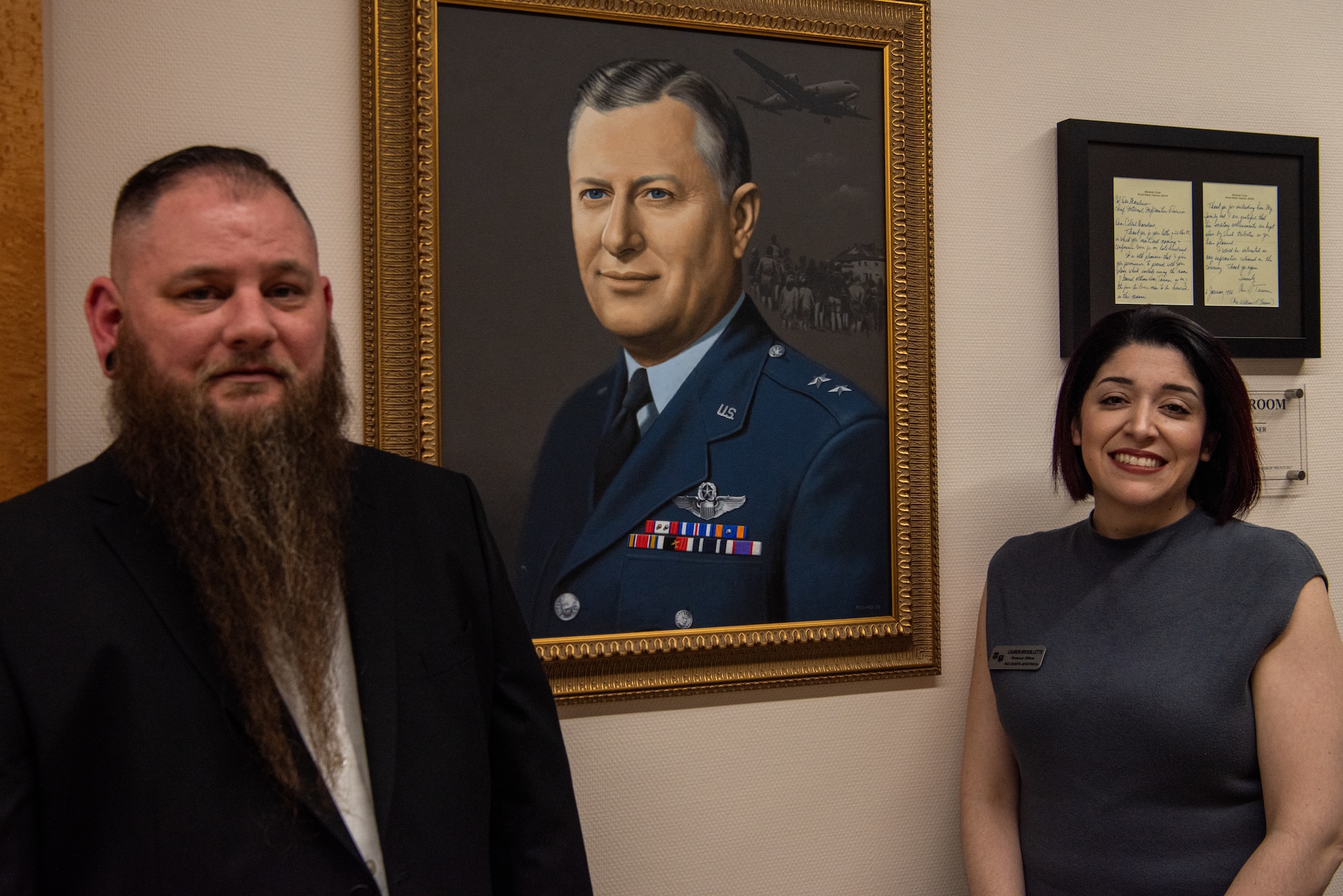 Lead designers pose in front of portrait.