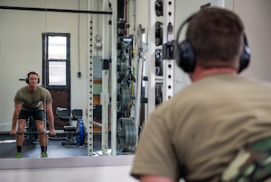 Someone deadlifts weights at a base gym.
