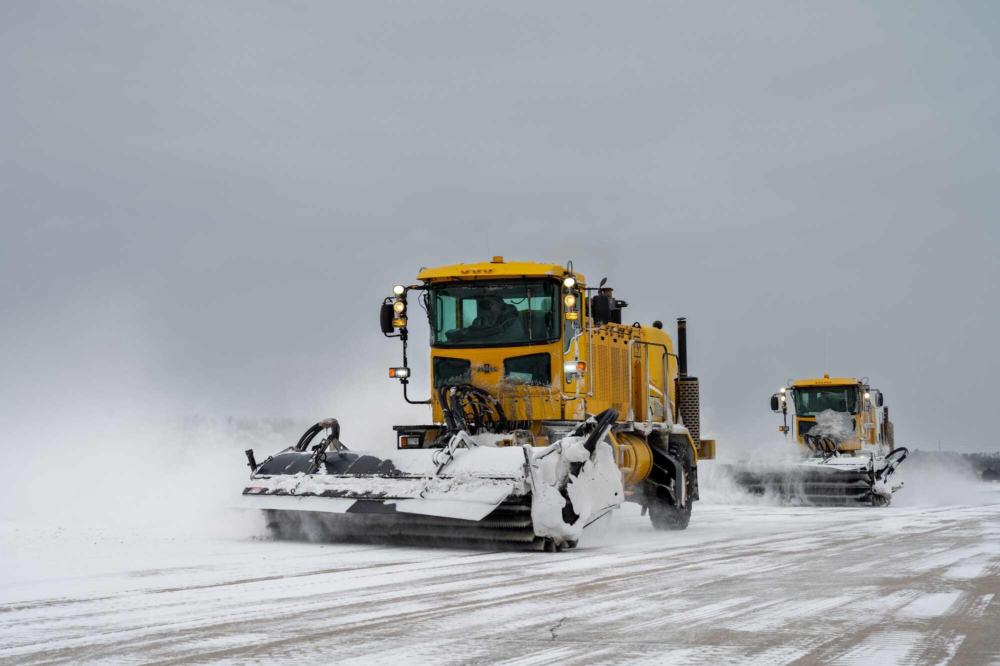 22nd Civil Engineer Squadron snow removal vehicles sweep snow on the flightline at McConnell Air Force Base, Kansas, Feb. 12, 2025. The engineering equipment operators strategically prioritized parts of McConnell to ensure operations return to normal as quickly as possible. (U.S. Air Force photo by Airman 1st Class Paula Arce)