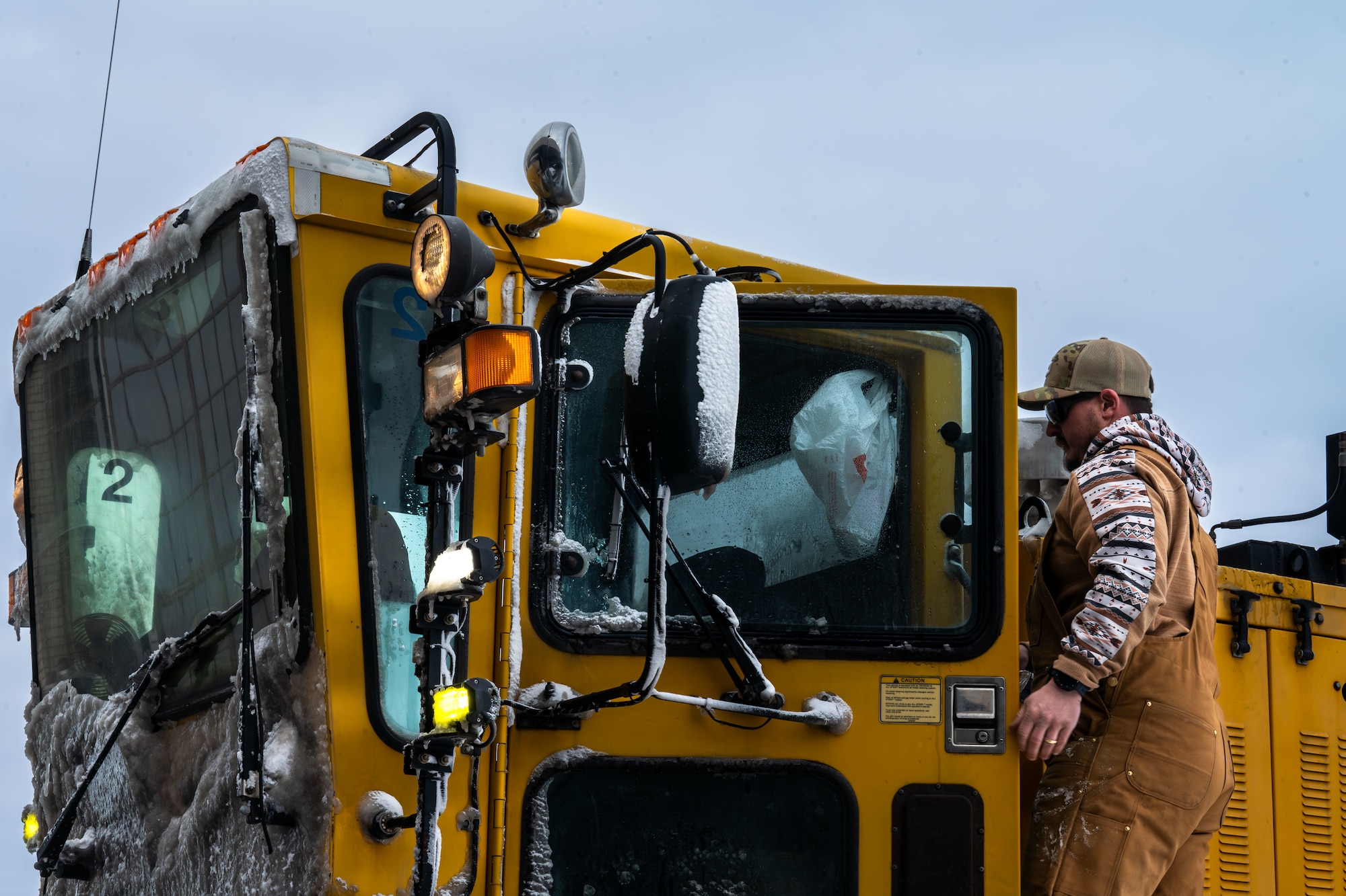 Matt Nall, 22nd Civil Engineer Squadron heavy equipment operator, climbs into a snow removal vehicle at McConnell Air Force Base, Kansas, Feb. 12, 2025. The engineering equipment operators prioritized cleaning the flightline to ensure flying operations could continue. (U.S. Air Force photo by Airman 1st Class Paula Arce)