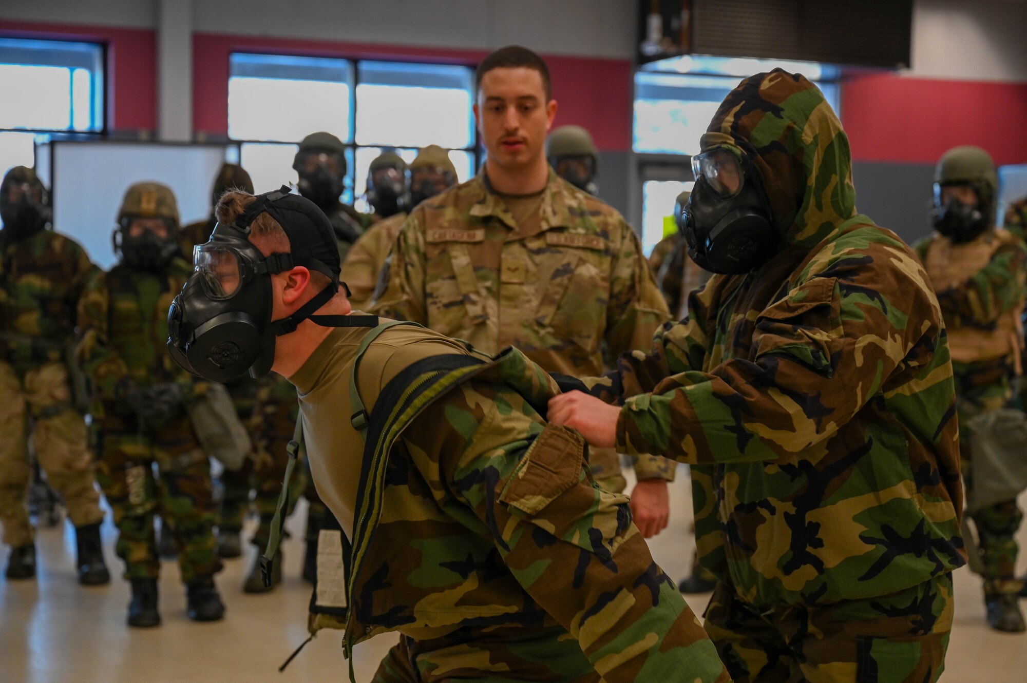 U.S. Airmen assigned to the 354th Logistics Readiness Squadron assist each other in doffing Mission Oriented Protective Posture gear during an expeditionary training week at Eielson Air Force Base, Alaska, Feb. 11, 2025.