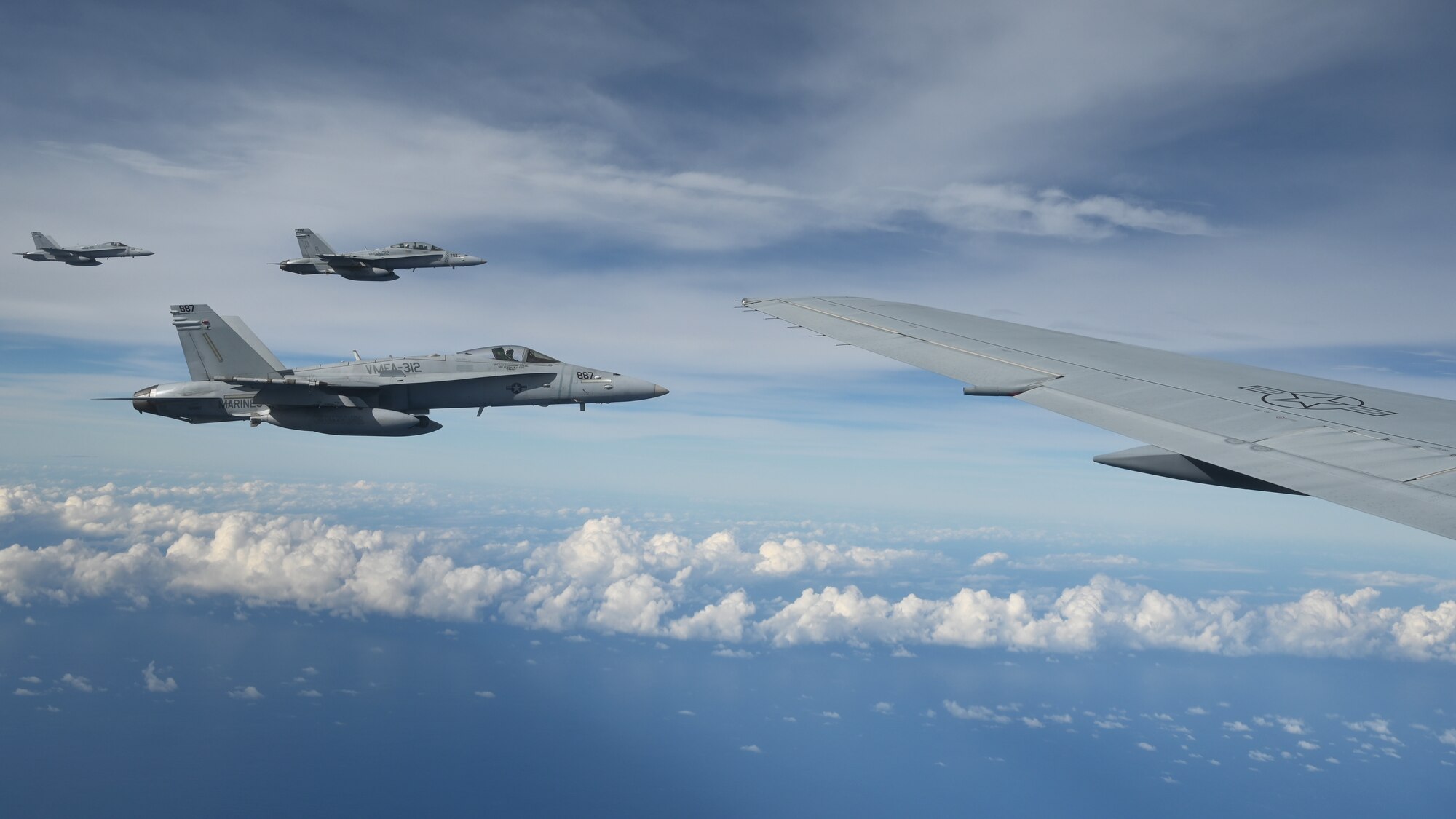 Three F/A-18D Hornet aircraft hover outside a the wing of a KC-46A Pegasus assigned to McConnell Air Force Base, Kansas, and flown by an 931st Air Refueling Wing aircrew, the Reserve Unit at Team McConnell, over the skies of Guam, Feb. 5, 2025.