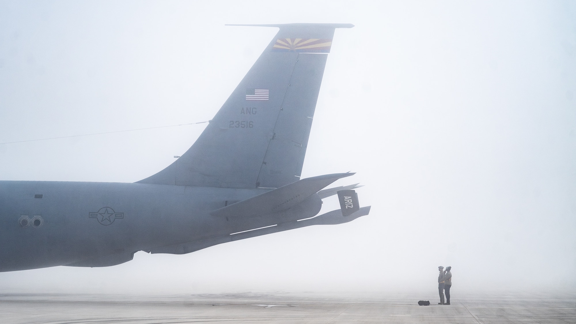 Airmen stand beside an aircraft in the fog