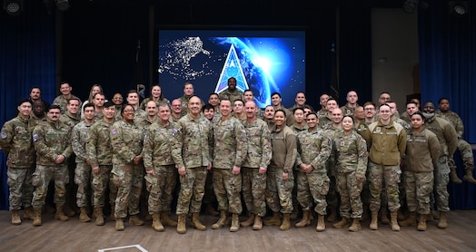  Guardians pose for a group photo. The Space Force symbol is displayed on a screen in the background.
