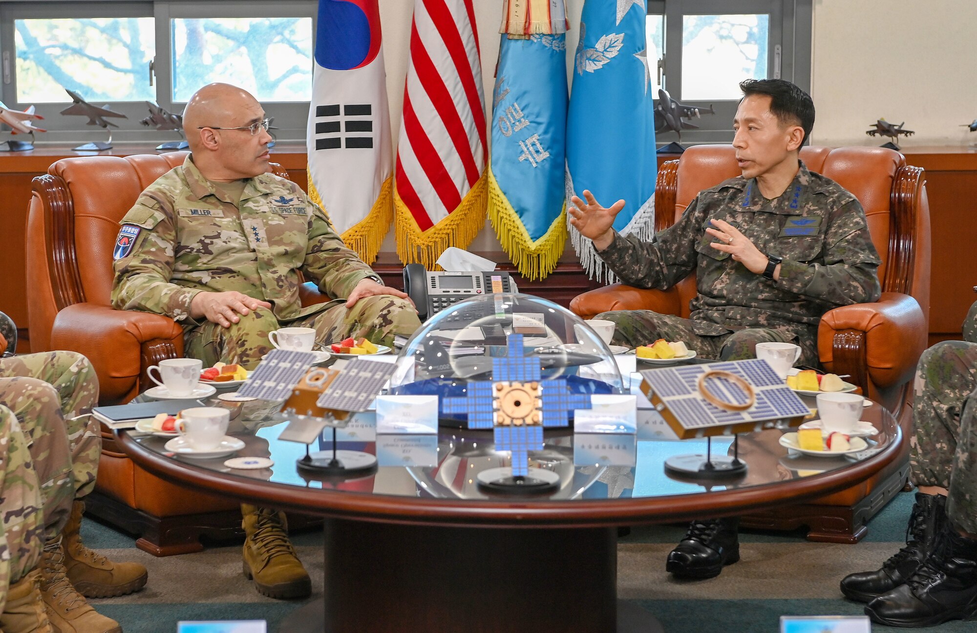 Engaged in conversation, a U.S. Space Force lieutenant general and a Republic of Korea Air Force lieutenant general sit in an official setting, with flags of the U.S., Republic of Korea, ROK Air Force Operations Command, and a general officer flag visible behind them.