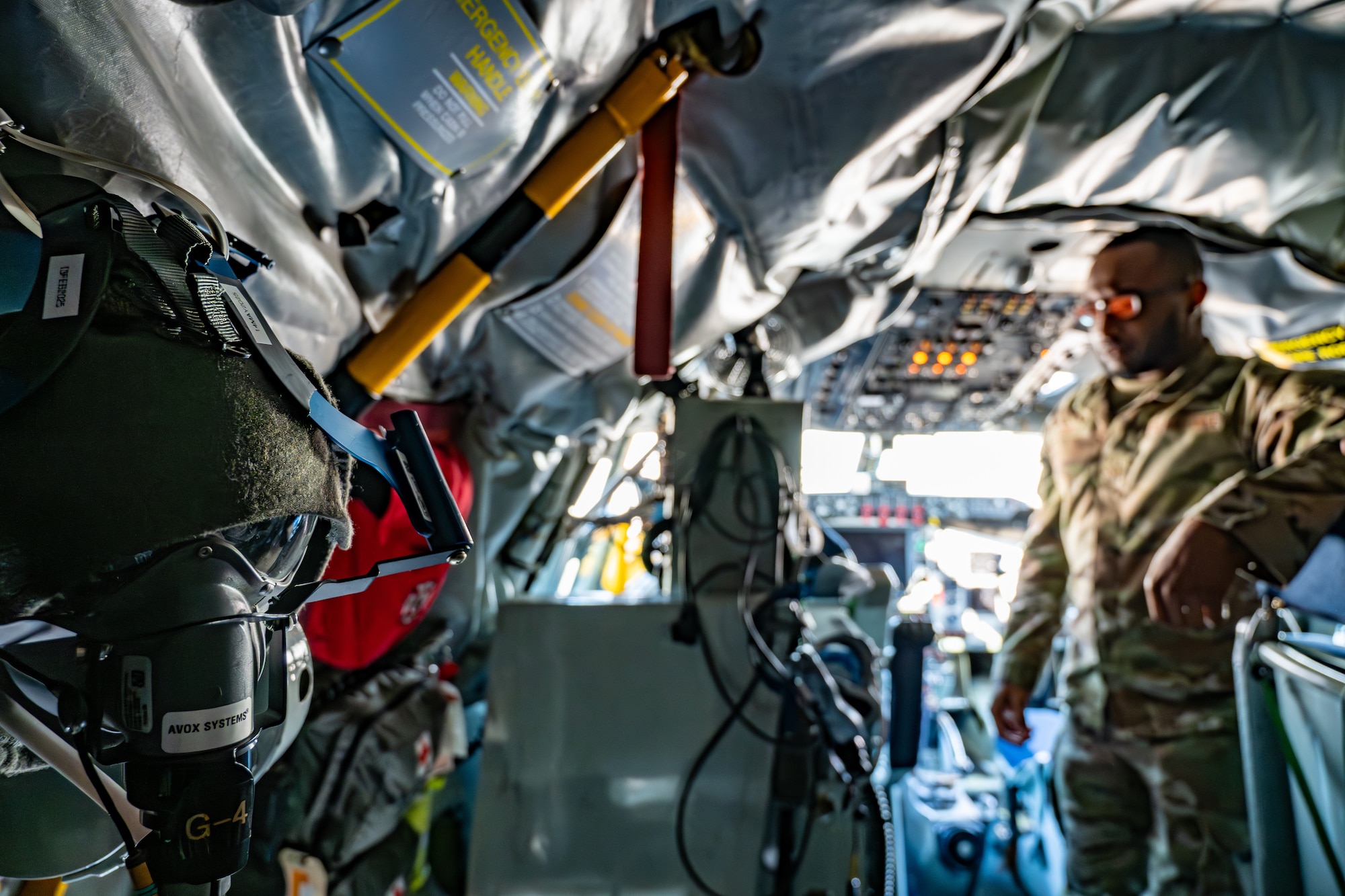 An Airman stands in an aircraft near flight safety equipment