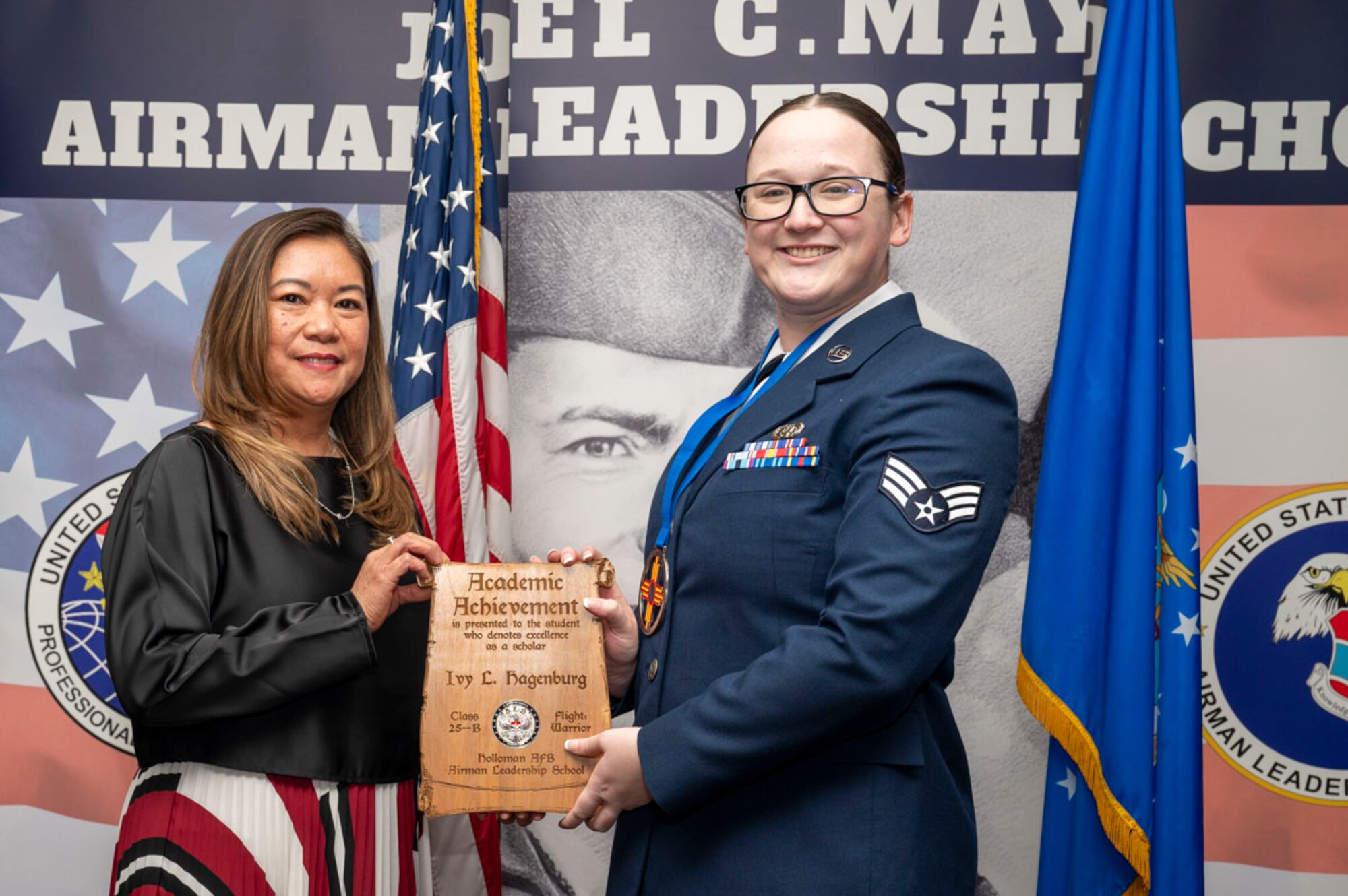 U.S. Air Force Senior Airman Ivy Hagenburg, right, Airman Leadership Graduate, accepts the Academic Achievement Award from Lany Cooper, Otero Federal Credit Union sponsor, during the graduation of Joel C. Mayo ALS Class 25-B at Holloman Air Force Base, New Mexico, Feb. 7, 2025. The academic award is presented to the student with the highest overall average on all academic evaluations and demonstrations of leadership. (U.S. Air Force photo by Senior Airman Michelle Ferrari)