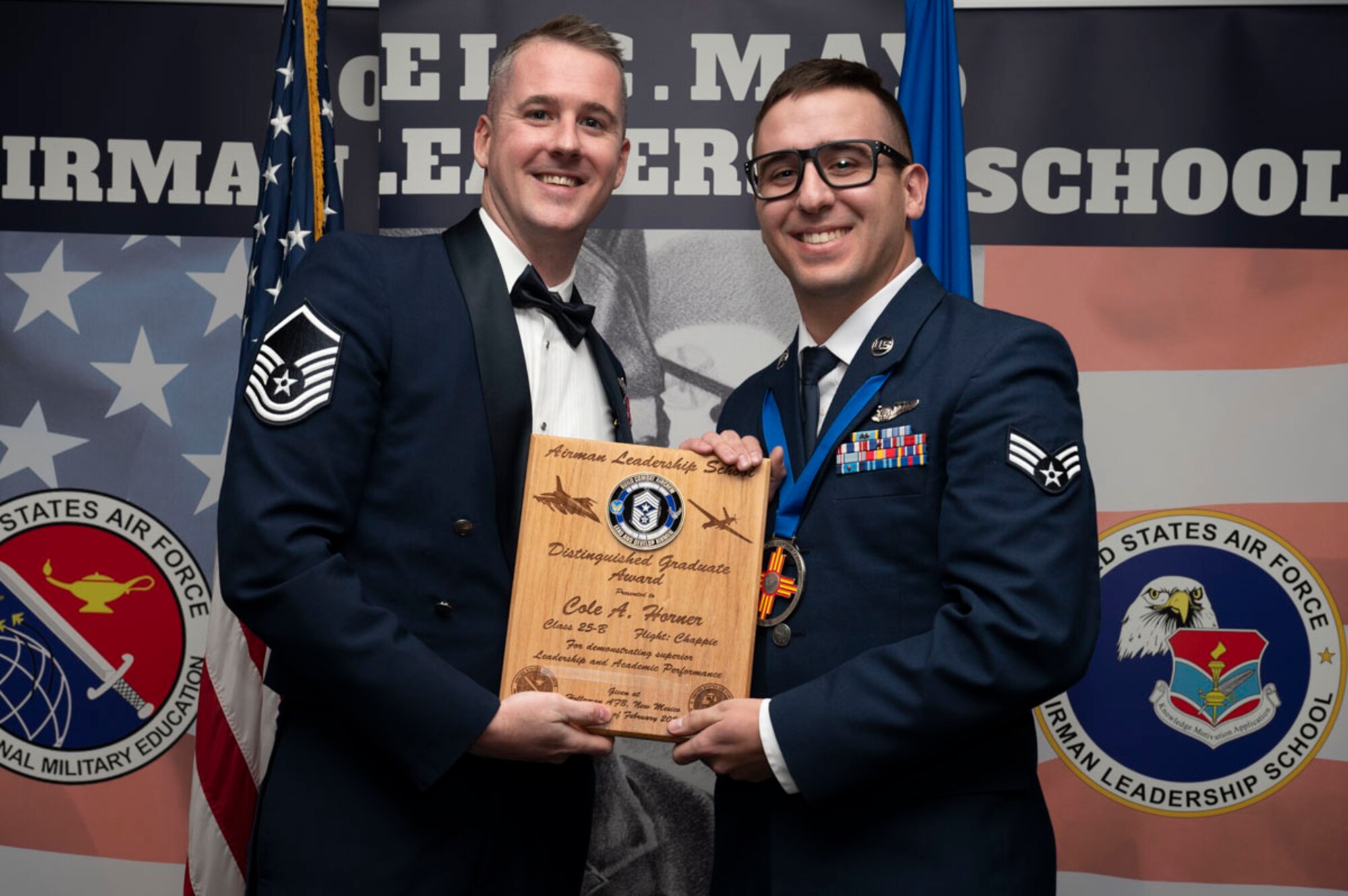 U.S. Air Force Senior Airman Cole Horner, right, Airman Leadership Graduate, accepts the Distinguished Graduate Award from U.S. Air Force Master Sgt. Gregory Saxon, 9th Attack Squadron operations superintendent, during the graduation of Joel C. Mayo ALS Class 25-B at Holloman Air Force Base, New Mexico, Feb. 7, 2025. The distinguished graduate award is presented to the top 10% of graduates for their performance in academic evaluations and demonstration of leadership. (U.S. Air Force photo by Senior Airman Michelle Ferrari)