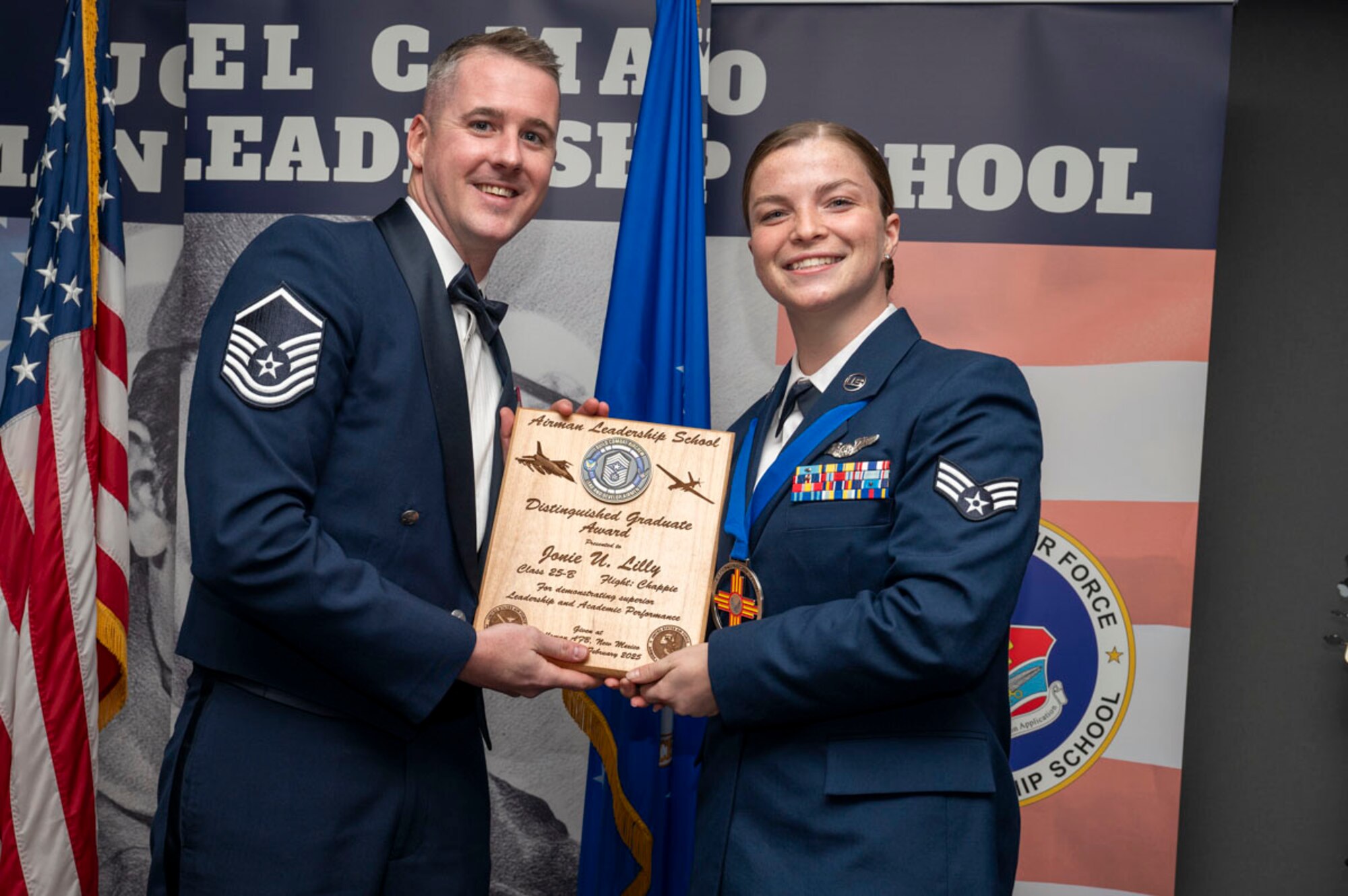 U.S. Air Force Senior Airman Jonie Lilly, right, Airman Leadership Graduate, accepts the Distinguished Graduate Award from U.S. Air Force Master Sgt. Gregory Saxon, 9th Attack Squadron operations superintendent, during the graduation of Joel C. Mayo ALS Class 25-B at Holloman Air Force Base, New Mexico, Feb. 7, 2025. The distinguished graduate award is presented to the top 10% of graduates for their performance in academic evaluations and demonstration of leadership. (U.S. Air Force photo by Senior Airman Michelle Ferrari)