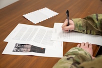 An Airman writes a letter on a piece of paper
