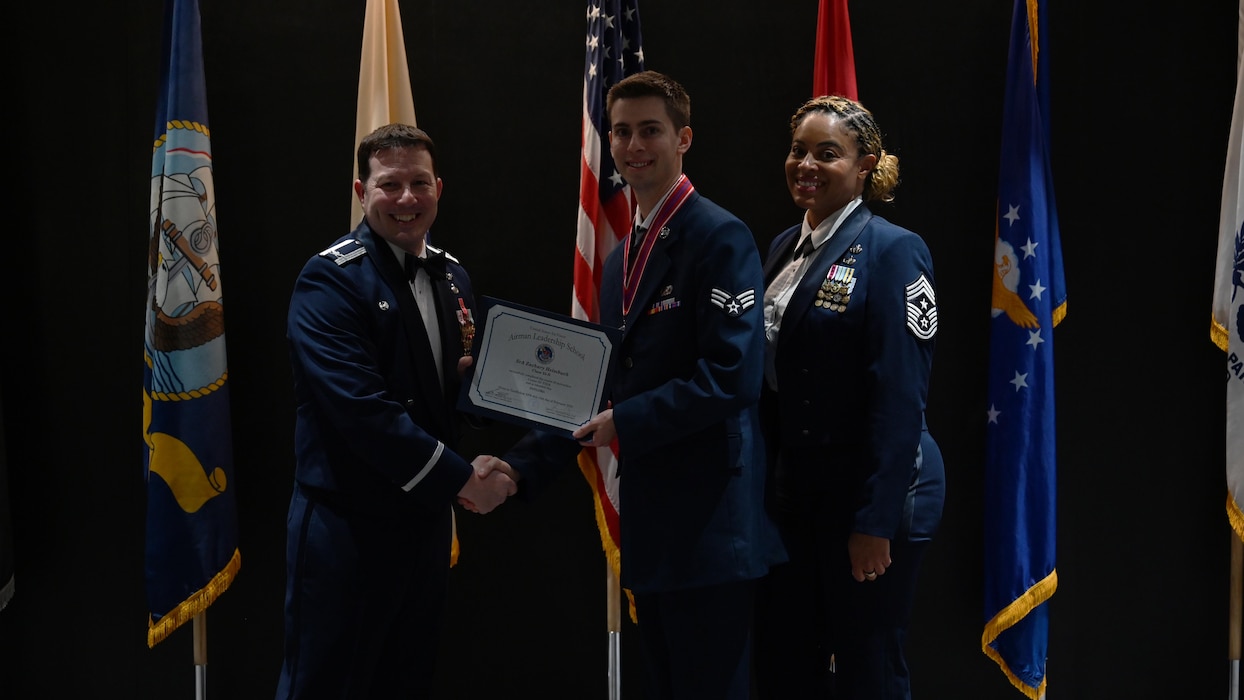 U.S. Air Force Col. Jason Gerber, 17th Training Group Commander, and Chief Master Sgt. Khamillia Washington, 17th Training Wing command chief, present Senior Airman Zachary Heimbuch, Airman Leadership School Class 25-B graduate, with the Airman Leadership School diploma during the ALS Class 25-B graduation at the Powell Event Center, Goodfellow Air Force Base, Texas, Feb. 13, 2025. ALS is a five-week course designed to prepare senior airmen to assume supervisory duties through instruction in leadership, followership and written and oral communication skills. (U.S. Air Force photo by Senior Airman Madi Collier)