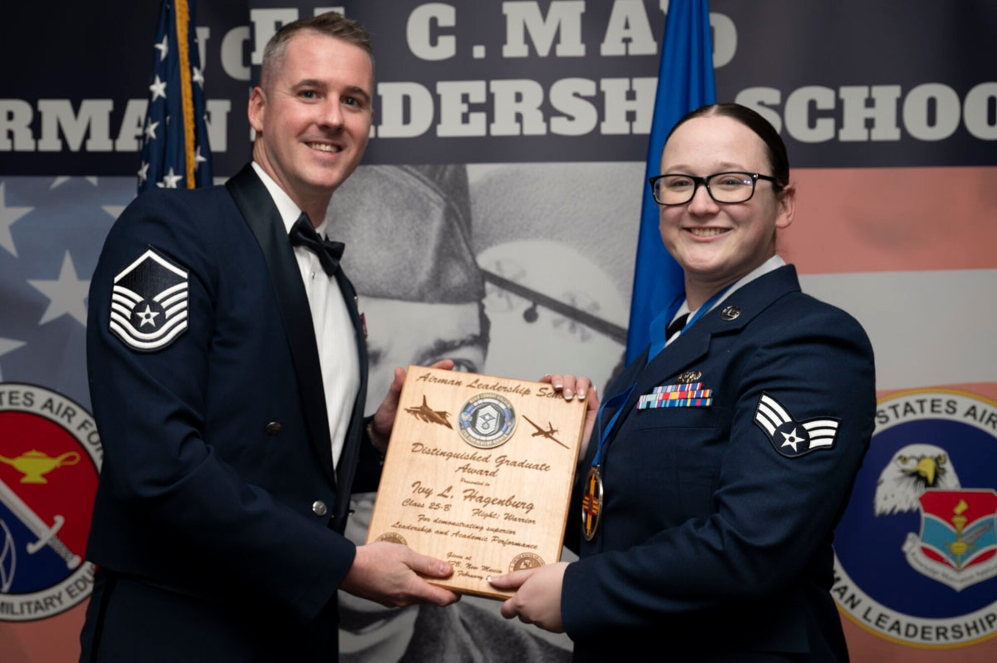 U.S. Air Force Senior Airman Ivy Hagenburg, right, Airman Leadership Graduate, accepts the Distinguished Graduate Award from U.S. Air Force Master Sgt. Gregory Saxon, 9th Attack Squadron operations superintendent, during the graduation of Joel C. Mayo ALS Class 25-B at Holloman Air Force Base, New Mexico, Feb. 7, 2025. The distinguished graduate award is presented to the top 10% of graduates for their performance in academic evaluations and demonstration of leadership. (U.S. Air Force photo by Senior Airman Michelle Ferrari)