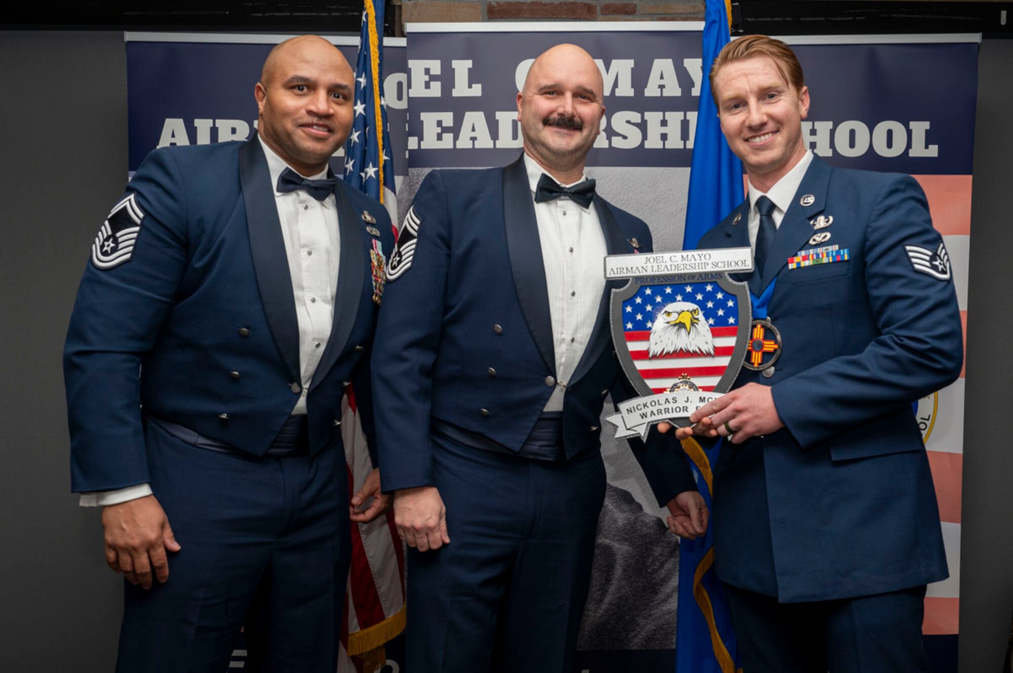 U.S. Air Force Staff Sgt. Nickolas McBride, right, accepts the Profession of Arms Award from U.S. Air Force Senior Master Sgt. Andre Thomas, 49th Wing Staff Agency religious affairs superintendent, and U.S. Air Force Chief Master Sgt. Jon Adams, 49th Operations Group senior enlisted leader, during the graduation of Joel C. Mayo ALS Class 25-B at Holloman Air Force Base, New Mexico, Feb. 7, 2025. The Profession of Arms Award recognizes the student who most embodies the profession of arms, which is demonstrated with a comprehensive understanding of the warrior ethos, oath of enlistment, and the airman’s creed. (U.S. Air Force photo by Senior Airman Michelle Ferrari)