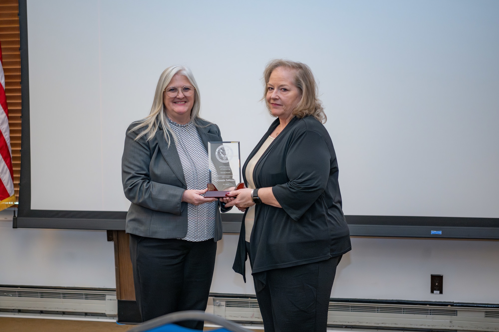 Arnold Engineering Development Complex Test Enterprise Contracting Support Branch Chief Barbara Newkirk, right, receives a plaque from AEDC Test Range Contracting Division Chief Rebecca Gardner on behalf of Contract Specialist LaLonnie Saltzman recognizing Saltzman as the 2024 fiscal year winner of the Air Force Test Center award for Outstanding Government Purchase Card Program during the AEDC Annual Awards ceremony Feb. 13, 2025, at Arnold Air Force Base, Tenn. (U.S. Air Force photo by Keith Thornburgh)