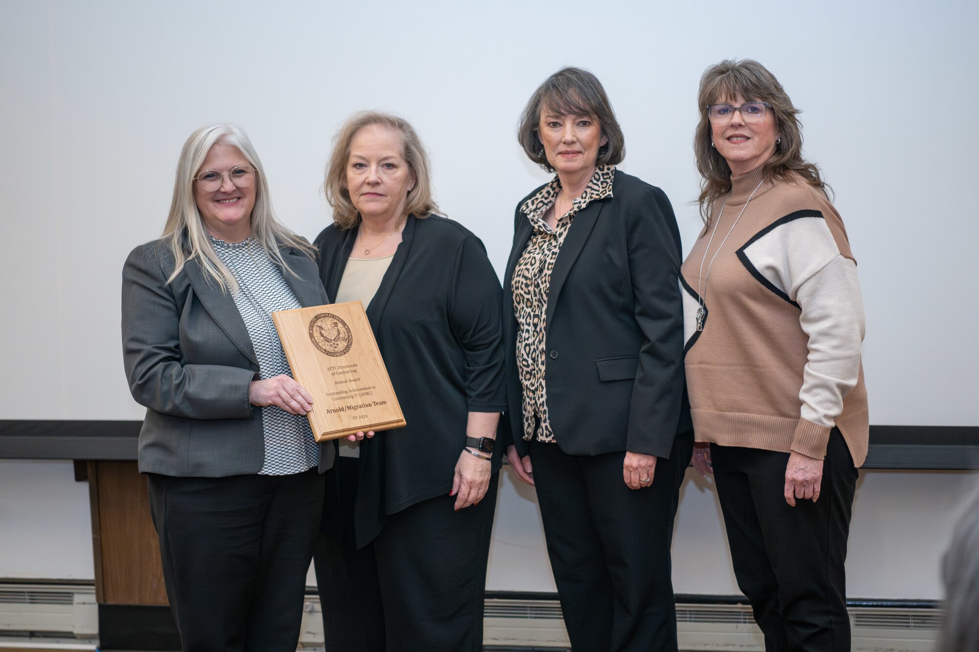 Arnold Engineering Development Complex Test Range Contracting Division Chief Rebecca Gardner, left, presents the Migration Team with a plaque recognizing the team as the 2024 fiscal year winner of the Air Force Test Center award for Outstanding Achievement in Contracting during the AEDC Annual Awards ceremony Feb. 13, 2025, at Arnold Air Force Base, Tenn. Also pictured from left are Test Enterprise Contracting Support Branch Chief Barbara Newkirk, Management Analyst Theresa Cates and Contracting Officer Patricia Henderson. (U.S. Air Force photo by Keith Thornburgh)