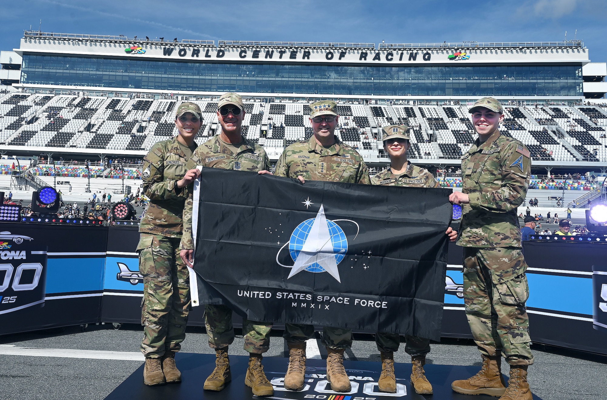 Space Force members stand on a stage holding Space Force flag.